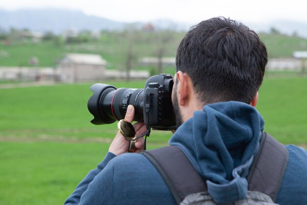 A man takes pictures in a green field during the day