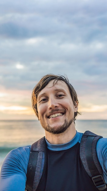 A man takes a selfie on the background of the sea and sunset vertical format for instagram mobile