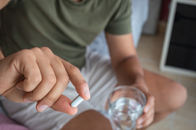 Man taking a melatonin pill to help him sleep. Concept of sleep problems or insomnia