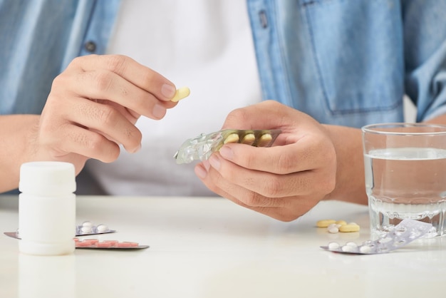 Man taking pill out from blister pack at home