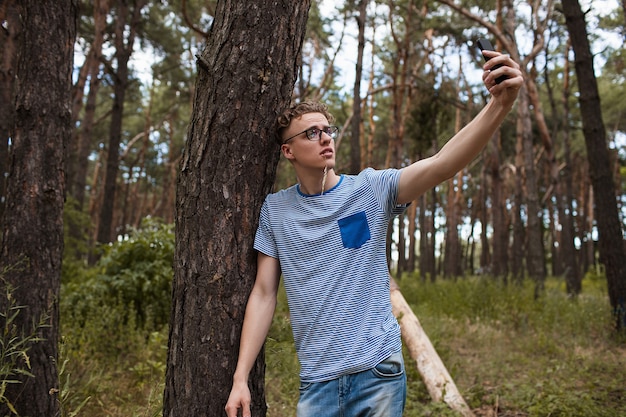  man taking selfie on phone in the forest. alone with nature. traveler lifestyle.