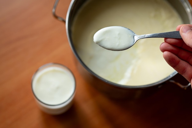 Man taking some yogurt from pan to cup for a meal Eating healthy dairy product for treating stomach