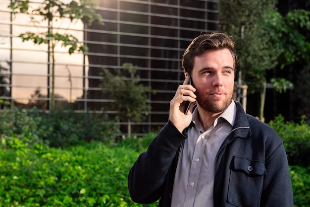 Man talking by phone next to an office building