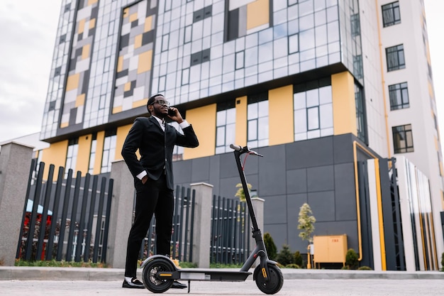 Man talking on the phone near an electric scooter Against the b