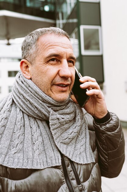 A man talking on a phone with a grey scarf