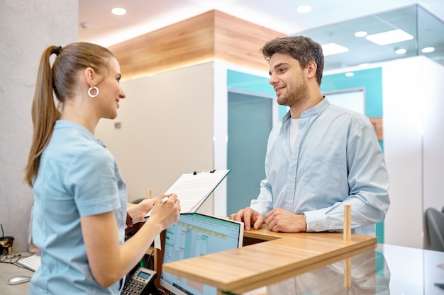 Man talking to professional receptionist in clinic