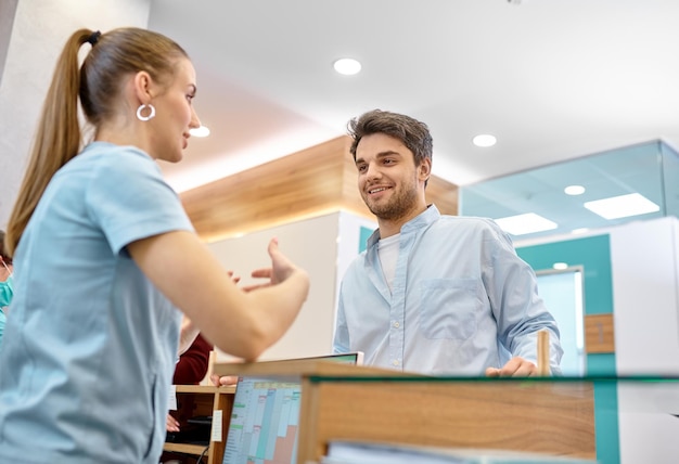 Man talking to professional receptionist in clinic