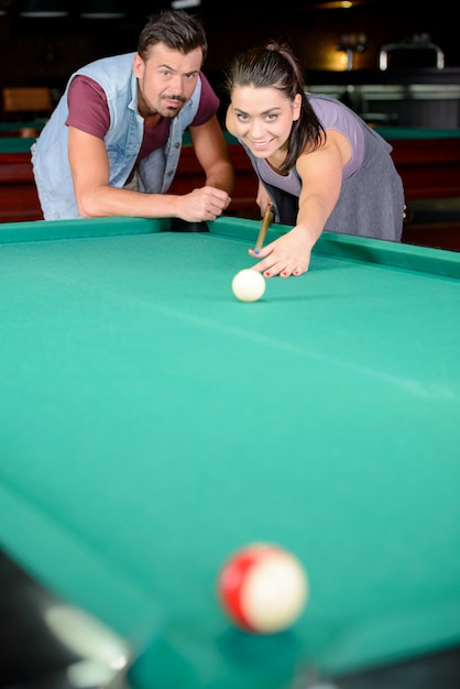 A man tells a girl how to hit the ball correctly.