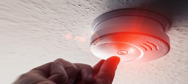 Man tested a smokedetector with a red warning light in a house. ideal for websites and magazines layouts.