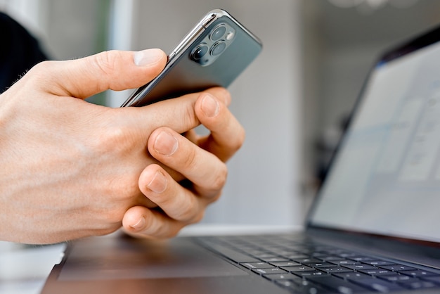 Man texting on phone while work on laptop . High quality photo