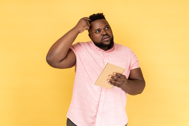 Man thinking over smart idea holding pencil and notebook to write plans todo list