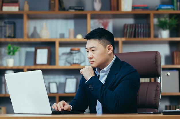 Man thinking working on laptop Asian in classic office boss working on project