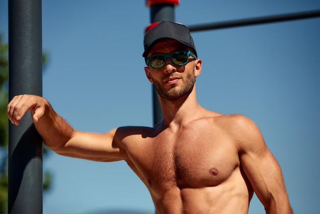 A man thinks about his body and health portrait of a sporty physique sports stadium in the Park short hair beard bare torso Sunny summer day Caucasian appearance