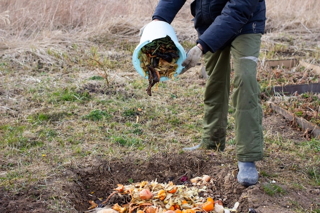 Man throwing away vegetable and fruit leftovers for composting outdoors in garden