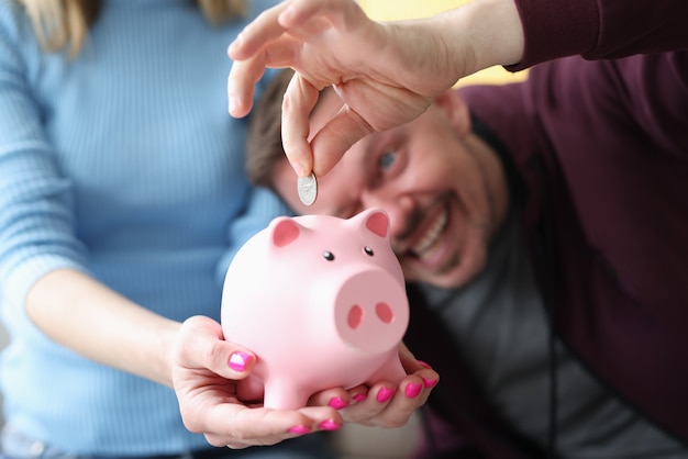 Man throws coin into piggy bank held by woman