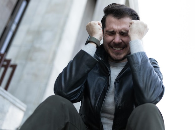 A man at the time of a panic attack sits in the city on the steps