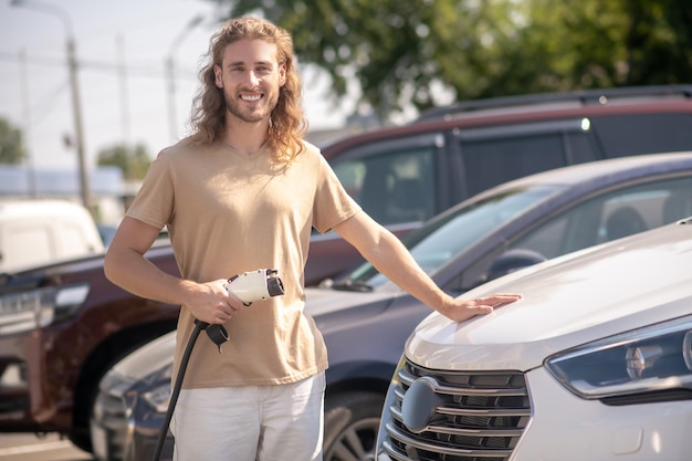 Man touching car hood looking at camera