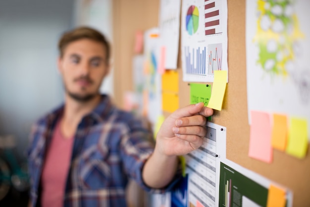 Man touching sticky note on the board in office