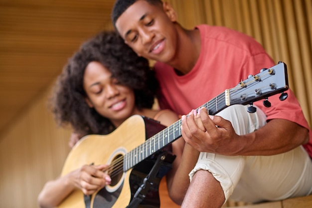 Man touching womans fingers on strings of guitar