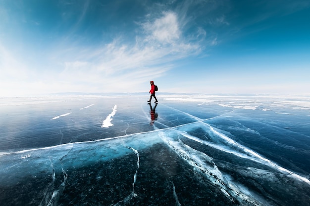 Man tourist walking on the ice of Baikal lake Winter landscape of Baikal lake Russia