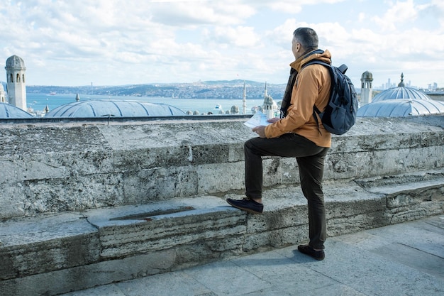 Man tourist with backpack map looking at Istanbul skyline Traveler in autumn day in Istanbul Turkey Travel concept