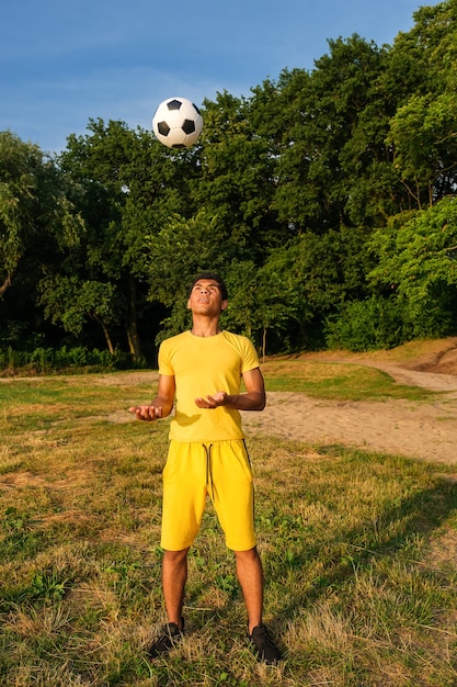 Man trains and improves soccer ball control on the grassy sandy riverbank