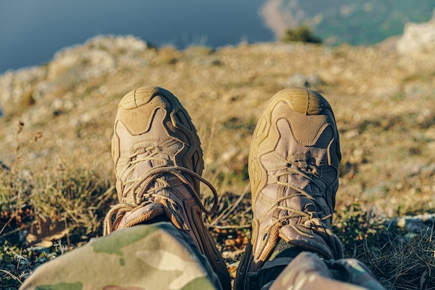 Man traveler in hiking boots sits on top