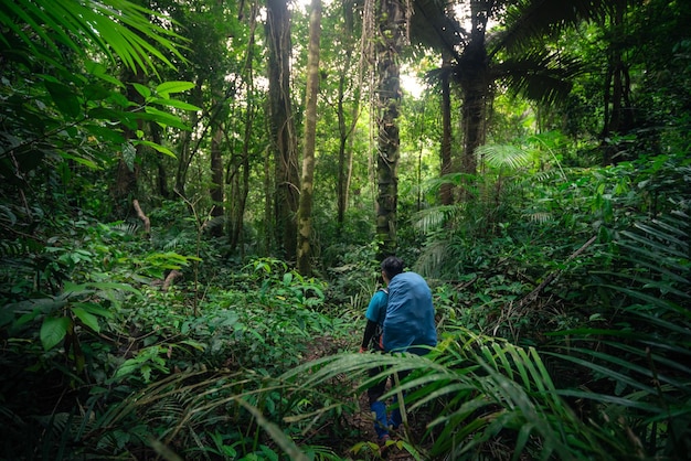 Man traveling with backpack hiking in mountains trekking and camping in rainforest