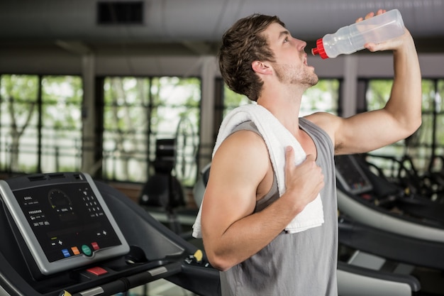 Man on treadmill drinking water at gym