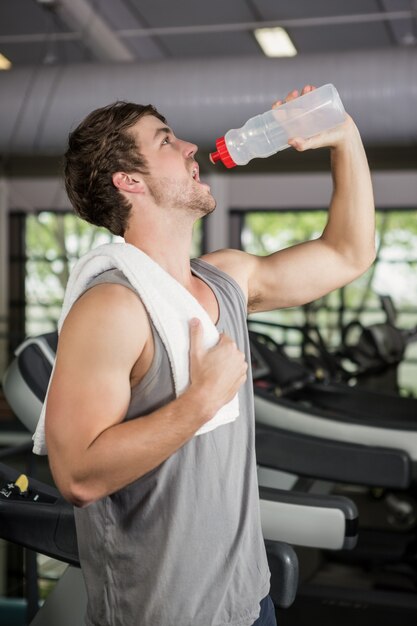 Man on treadmill drinking water at gym