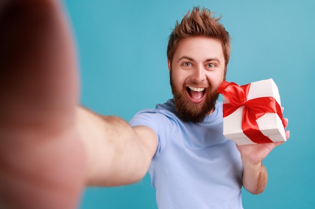 Man in Tshirt looking at camera with happy smile POV point of view of photo holding present box