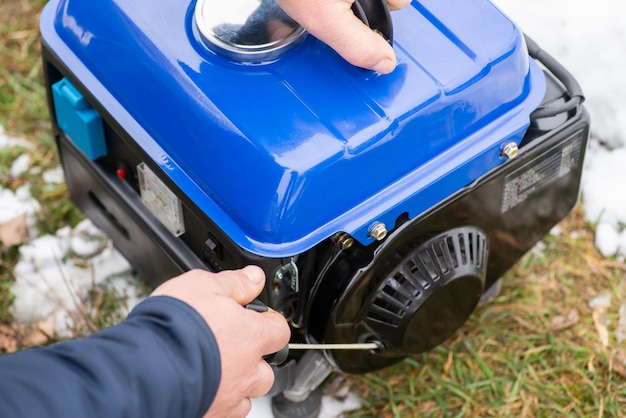 Man turning on the blue generator outdoors close up