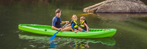 A man and two boys in a kayak on the river happy childhood banner long format