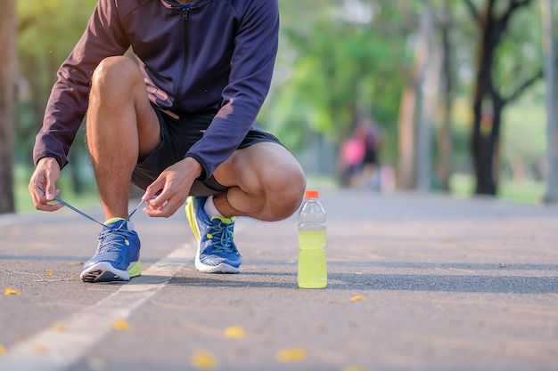 man tying running shoes in the park, male ready for jogging and exercise