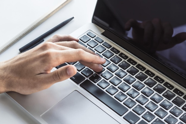 Photo man typing on laptop keyboard in sunny office business and technology concept close up