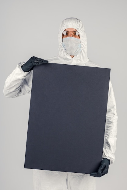 A man in a uniform and face mask holding a placard Concept of healthcare and medicine