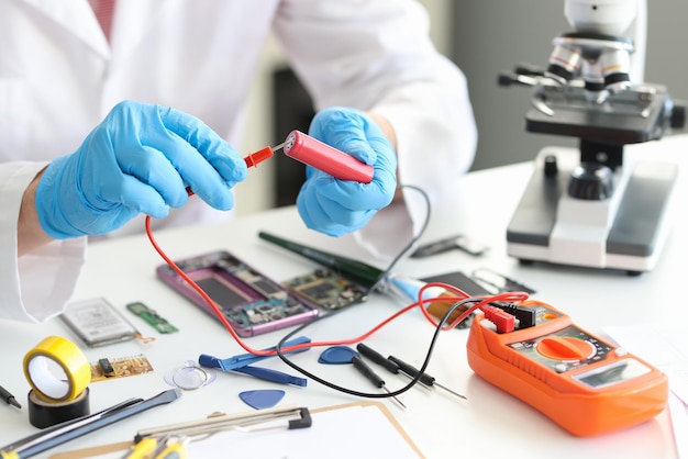 A man in uniform with voltmeter and a red battery in his hands