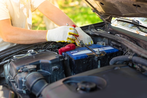 A man unscrews a car battery mount Battery repair and replacement