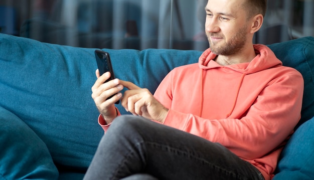 A man uses a smartphone on his home couch while relaxing at home applications calls internet concept high quality photo