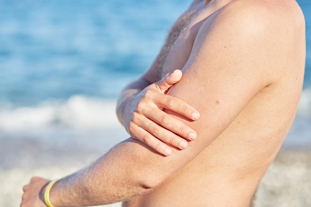 Man uses sun cream for a safe tan with high SPF on the beach Close up High quality photo