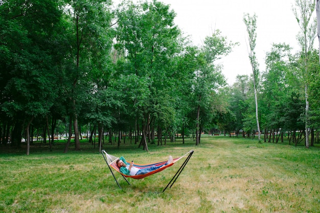 Man using an app on his mobile phone white swinging in a hammock