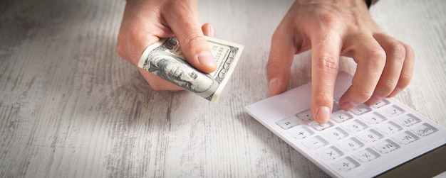 Man using calculator and holding dollars