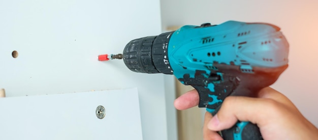 Man using a cordless screwdriver assembling furniture at home Carpenter working with electric screwdriver on the work