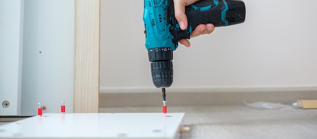 Man using a cordless screwdriver assembling furniture at home Carpenter working with electric screwdriver on the work