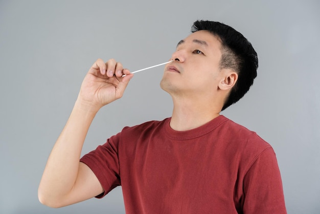 Man using coronavirus(covid-19) rapid antigen self test kit (atk) at home with a cotton nasal swab