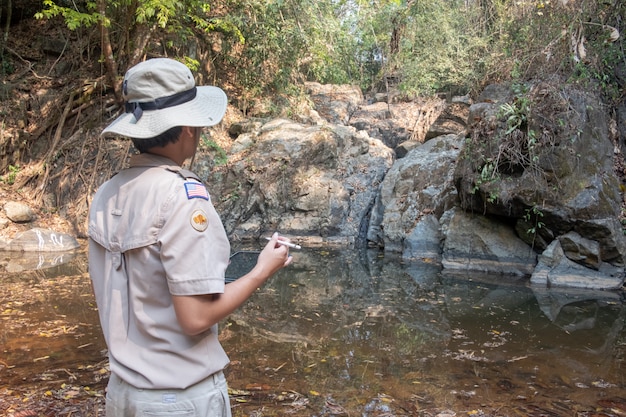 man using electronic devices to explore an arid waterfall.