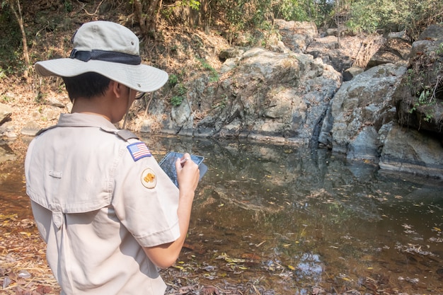 man using electronic devices to explore an arid waterfall.