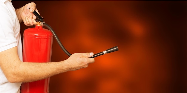 Man using fire extinguisher against grey background