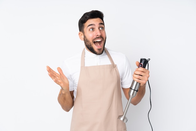 Man using hand blender isolated on white wall with surprise facial expression