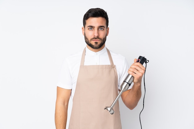 Man using hand blender on white keeping arms crossed